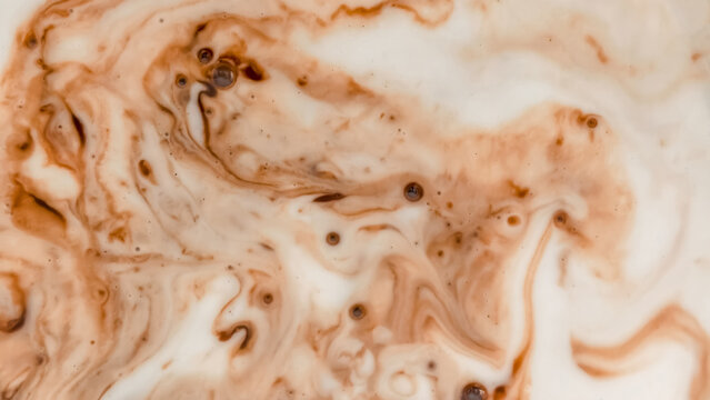 Abstract macro background of chocolate swirls with milk or cream texture.