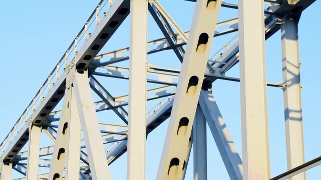 Abstract geometric pattern with bright blue sky, metal bridge structures form unique shape, sunny day.