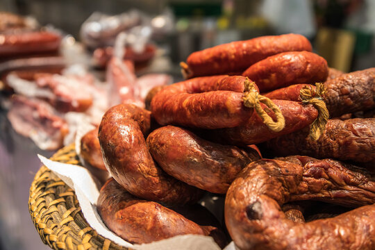 Primer plano de ristras de chorizo curado artesanal expuestas sobre un mostrador. Vista detallada de productos c&aacute;rnicos t&iacute;picos de la gastronom&iacute;a tradicional.