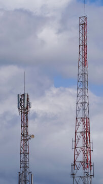 High Steel Telecommunication Towers Standing Against a Partly Cloudy Blue Sky Background for Modern Data Connectivity