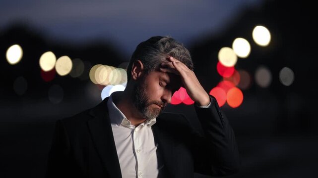 Stressed office worker experiencing stress from corporate life. Headache man in suit dealing with stress and emotional pain. Stressed business man suffering stress induced migraine.