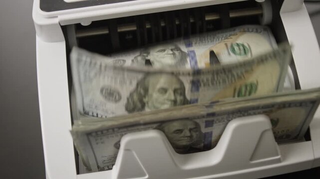 Money counting machine processing dollar bills in motion. Banking operation and finance concept with money movement. Counting money in motion. Counting dollar notes in a banking machine.