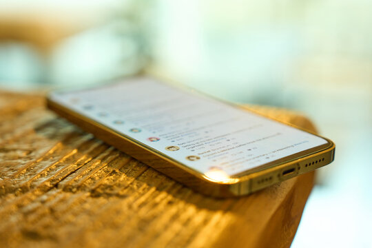 Smartphone displaying social media timeline on wooden table with natural light