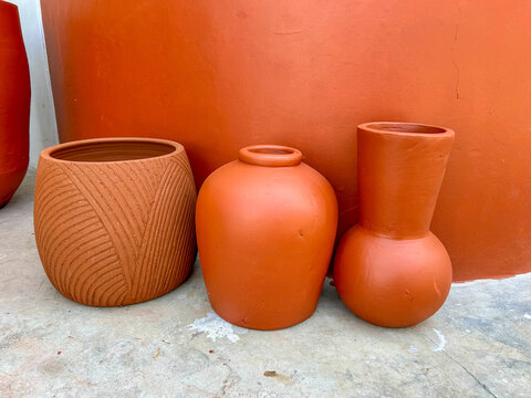 three minimalist terracotta clay pots and vases on concrete floor background