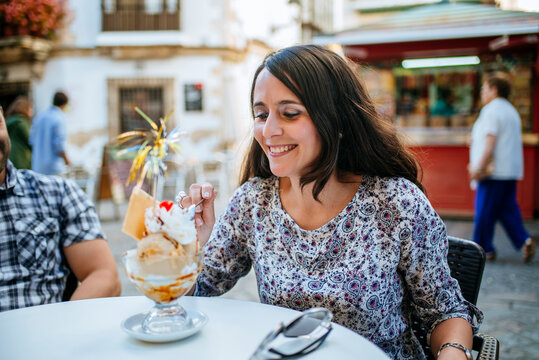 Woman eating ice cream in a street cafe.