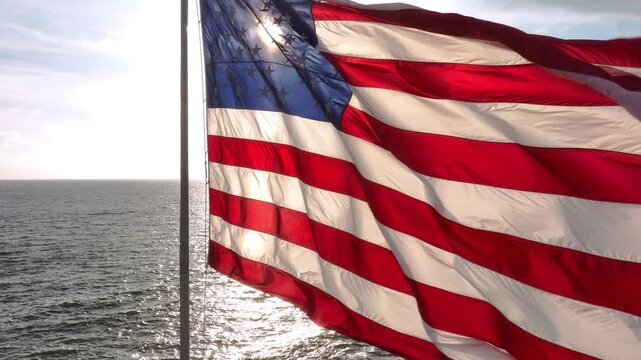 American flag waving on marine horizon. Flag USA flying over sea. American flag close-up in motion.