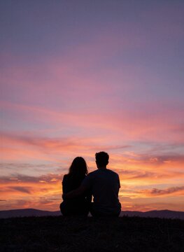 Captures Silhouette Of Two Individuals Sitting Close Together Against Backdrop Sunset Sky Main Subjects Adults Given Size Relative To However Specific