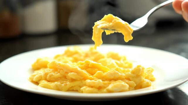 Fork to pick up the scrambled eggs on the plate, pick up the smooth scrambled eggs with the fork