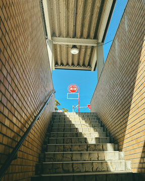 Low angle view of a Japanese fire hydrant sign in a clear blue sky from a tiled staircase