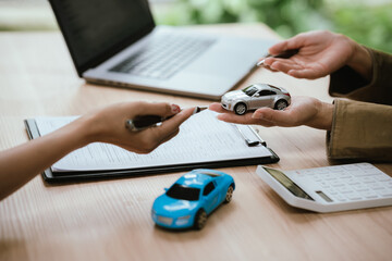 Fototapeta premium Close-up of a car sales or leasing consultation, with a miniature vehicle presented to a customer, symbolizing auto financing, ownership transfer, vehicle purchase, and rental services.