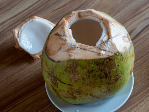 Fresh young green coconut opened and ready to drink showing soft white coconut meat inside