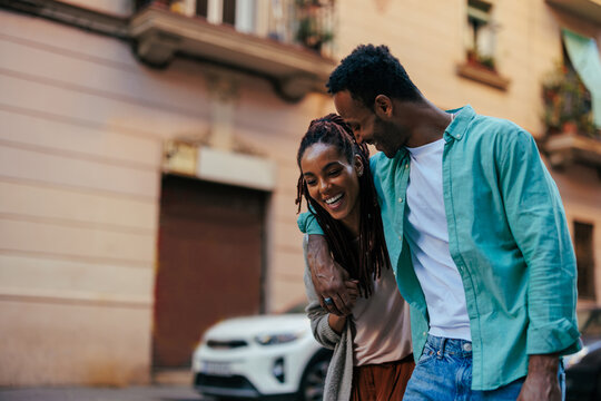 Happy diverse couple walking together on city street