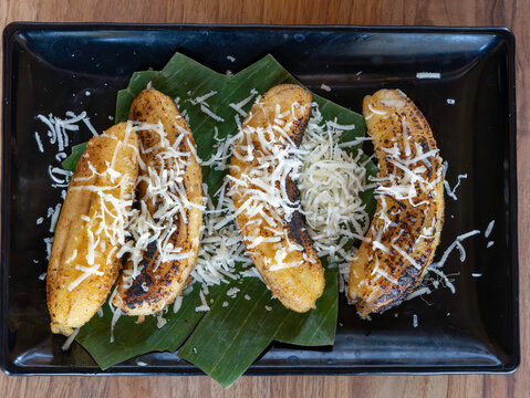 Grilled bananas with grated cheese served on banana leaf, traditional Indonesian snack Pisang Bakar