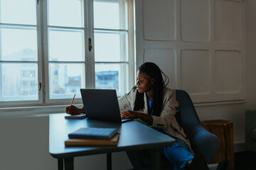 Young Black woman studying at desk with laptop