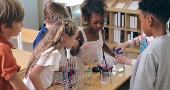 Excited diverse students watch a dry ice smoke experiment during a fun science lesson in the classroom.