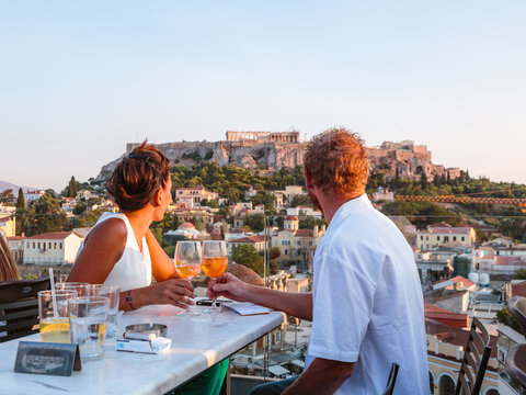 Couple drinking and enjoying the view of the Acropolis at sunset, Athens, Greece