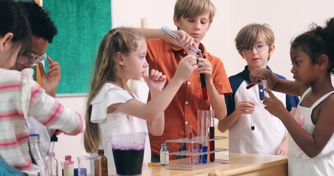 Diverse young children conduct a colorful chemistry experiment using test tubes and pipettes in a classroom.