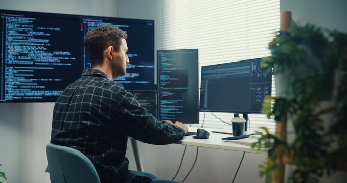 Young Caucasian male programmer writes code using multiple screens in home office workspace. AI development, cybersecurity, network database system, software engineering, remote tech startup concept.