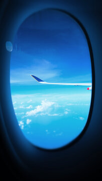 an aerial view from a plane window, airplane wing and clouds view. the blue, clear sky and beautiful clouds with the wings of the airplane that can see outside the window. singapore airlines
