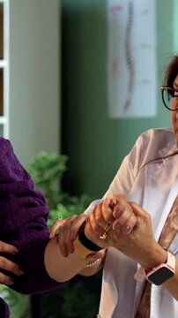 Indian lady physiotherapist examining wrist pain of young female patient during detailed consultation in modern clinic, highlighting senior expertise in joint assessment and rehabilitation care