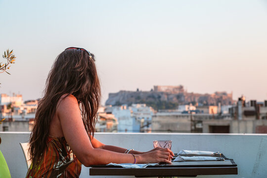 Woman at a restaurant enjoying the view of the Acropolis at sunset, Athens, Greece