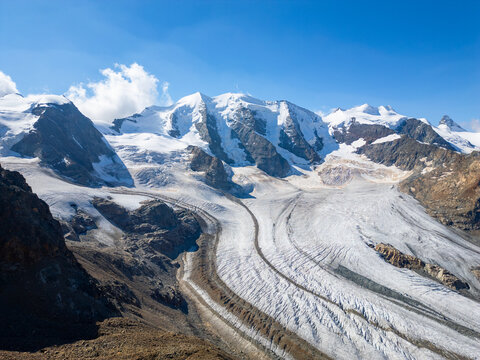Piz Palu towers majestically over the Pers Glacier, showcasing the rugged beauty of the Swiss Alps. Snow-capped peaks and a serene landscape create a breathtaking scene in clear weather.