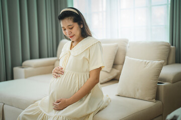 Obraz premium Asian Pregnant middle aged mother portrait. Pregnant happy Woman touching her belly, caressing her belly and smiling close-up. Healthy Pregnancy concept.