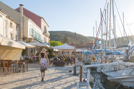 Woman walking in the harbour of Fiskardo at sunset, Kefalonia, Greek Islands, Greece
