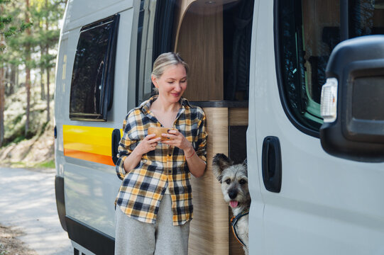 Woman with dog enjoys morning coffee by camper van