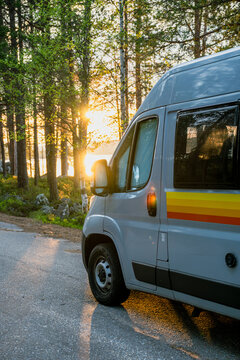 Camper van parked on a forest lake at golden sunset in Finland