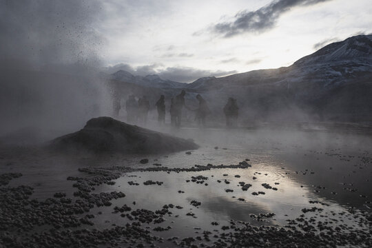 Silhouettes of people watching a geothermal geyser