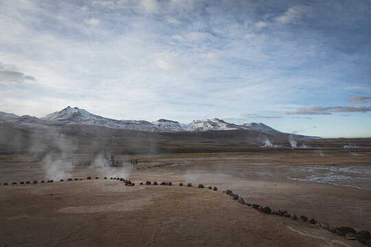 Geothermal field steams below snow capped mountains