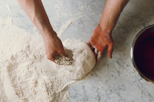 Pizza maker kneads dough and shapes pizza pan