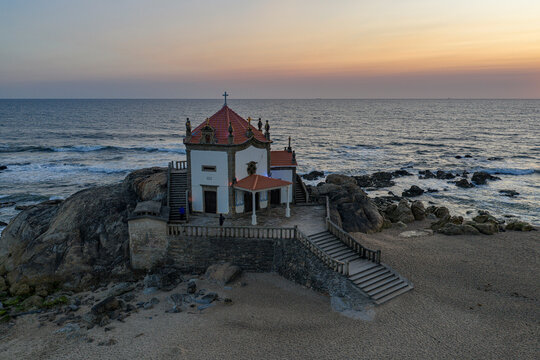 Capela do Senhor da Pedra chapel on a rocky beach at twilight
