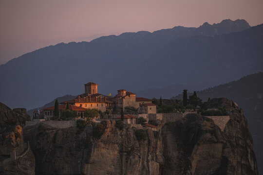 Ancient Meteora monastery on a cliff at sunset