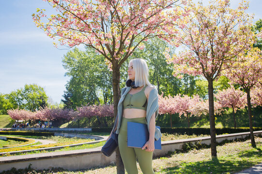 Beautiful blonde sporty woman going to outdoor online workout with