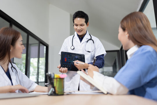 Professional Asian doctor presenting digital medical scans to colleagues during a team meeting, Healthcare and medical team concept.