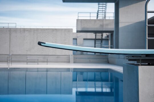 A professional diving springboard curving over calm blue pool water.
