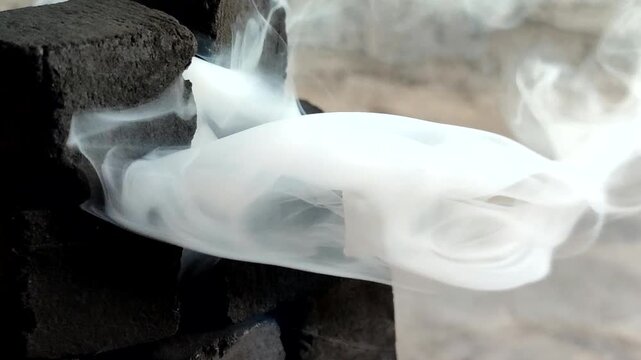 Burning charcoal briquettes emitting thick white smoke