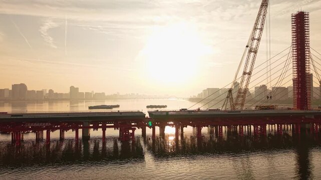 Aerial view of bridge sections being dismantled with a large crane over a river
