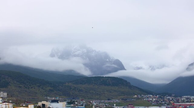 Monte Olivia mountain peak hidden behind low clouds above Ushuaia, Tierra del Fuego, Argentina. View of dramatic Patagonian landscapes, glacial terrain, and coastal nature in South America.