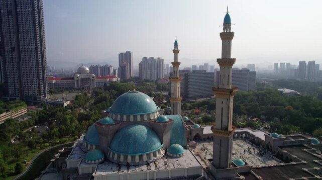 Drone side profile shot featuring Islamic architecture and city structures surrounding the Federal Territory Mosque.