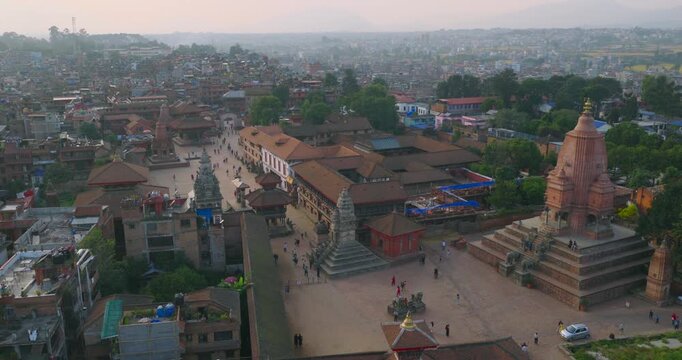 Drone captures a smooth orbiting movement around the core of Bhaktapur Durbar Square, circling above the historic stone temples, ancient brick palaces, and sprawling traditional architecture.