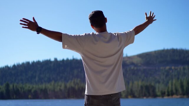 Low angle shot of a man standing outdoors with his arms wide open, capturing a strong feeling of freedom, liberation, openness, and connection with nature.