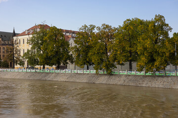 Obraz premium High flooded river water near a historic European city embankment with a cathedral and sandbag protection barriers along the promenade. Natural disaster and urban risk management