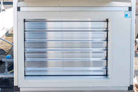 A close-up shot of an industrial ventilation system component, specifically an air control damper with multi-blade aluminum louvers.
