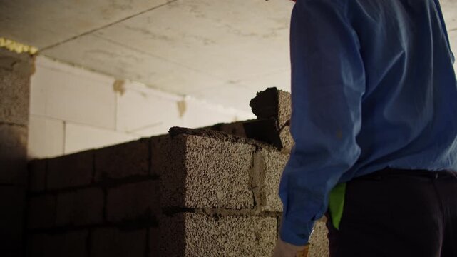 Builder constructing interior concrete block partition wall