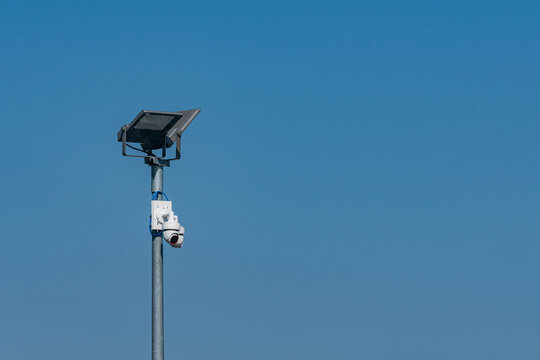 Solar panel with security camera stands under blue sky