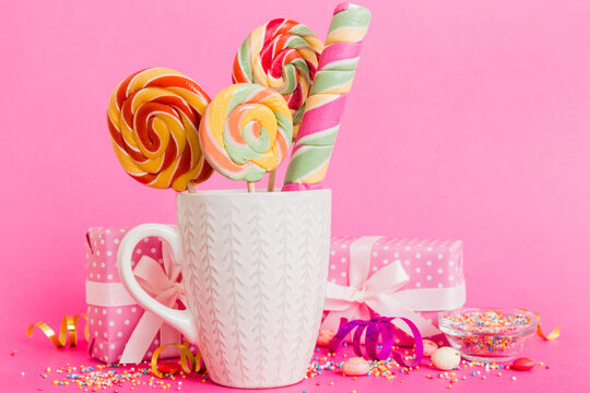 Colorful candies in cup on table on light background background. Large swirled lollipops. Creative concept of a jar full of delicious sweets from the candy store