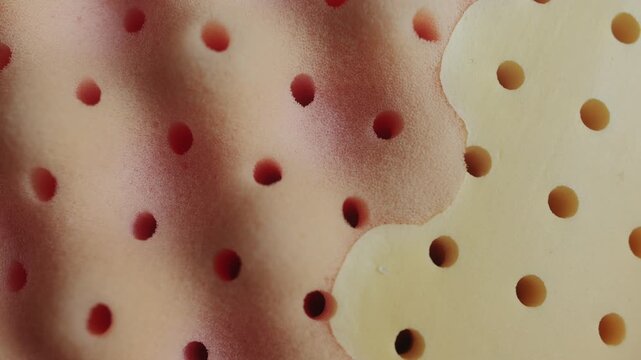 Close-up of perforated memory foam texture with soft rounded shapes and breathable structure. Abstract background representing comfort, support, and modern material design.